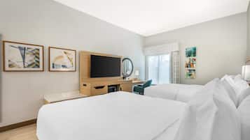 Una habitación de hotel con dos camas, televisión, escritorio y obras de arte en las paredes.