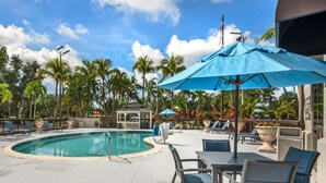 A pool area with lounge chairs, a gazebo, and a blue umbrella. - Hampton Inn Fort Myers-Airport & I-75 (Fort Myers)