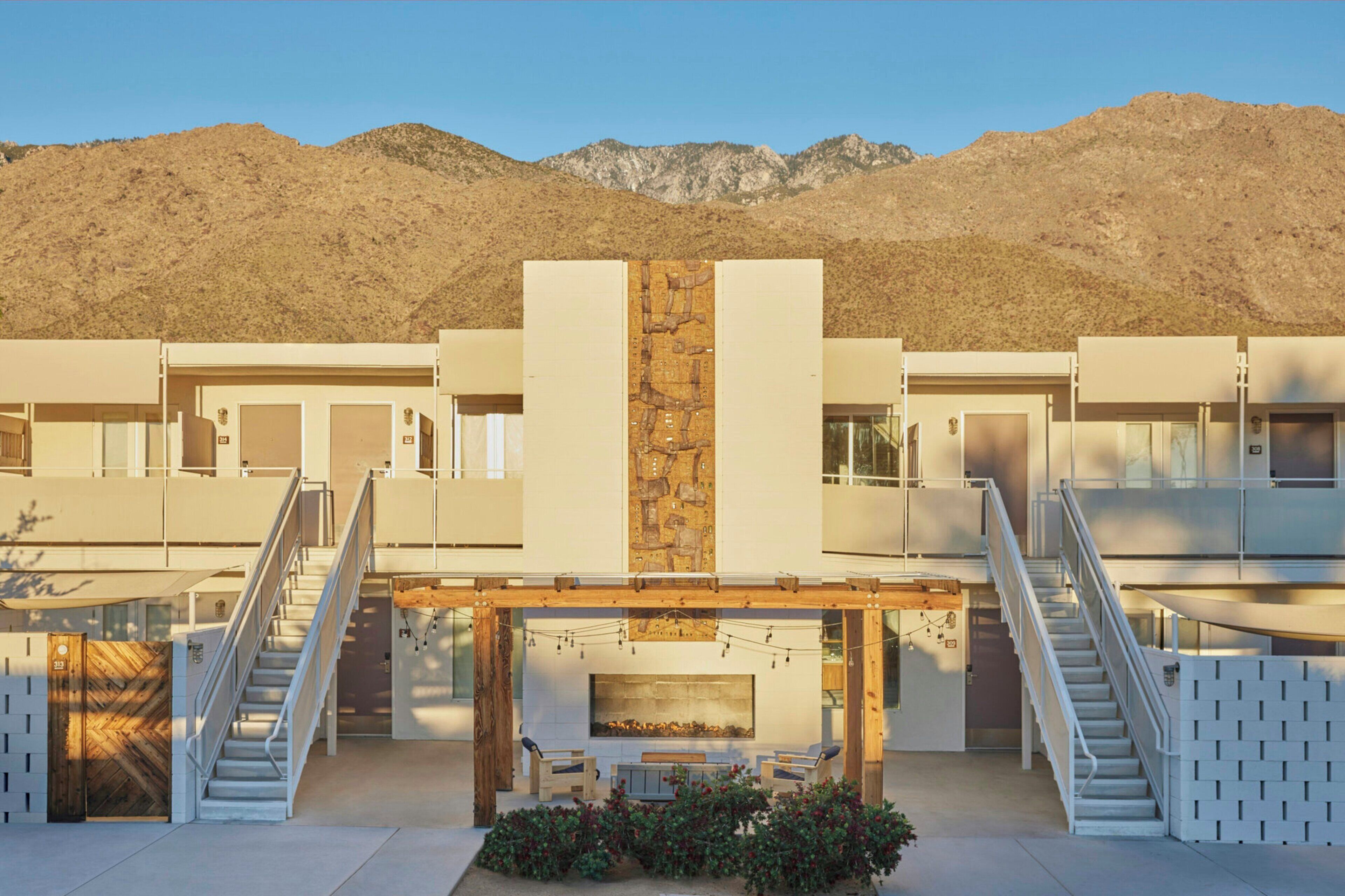 A modern building with a central courtyard, two staircases, and a mountain backdrop.
