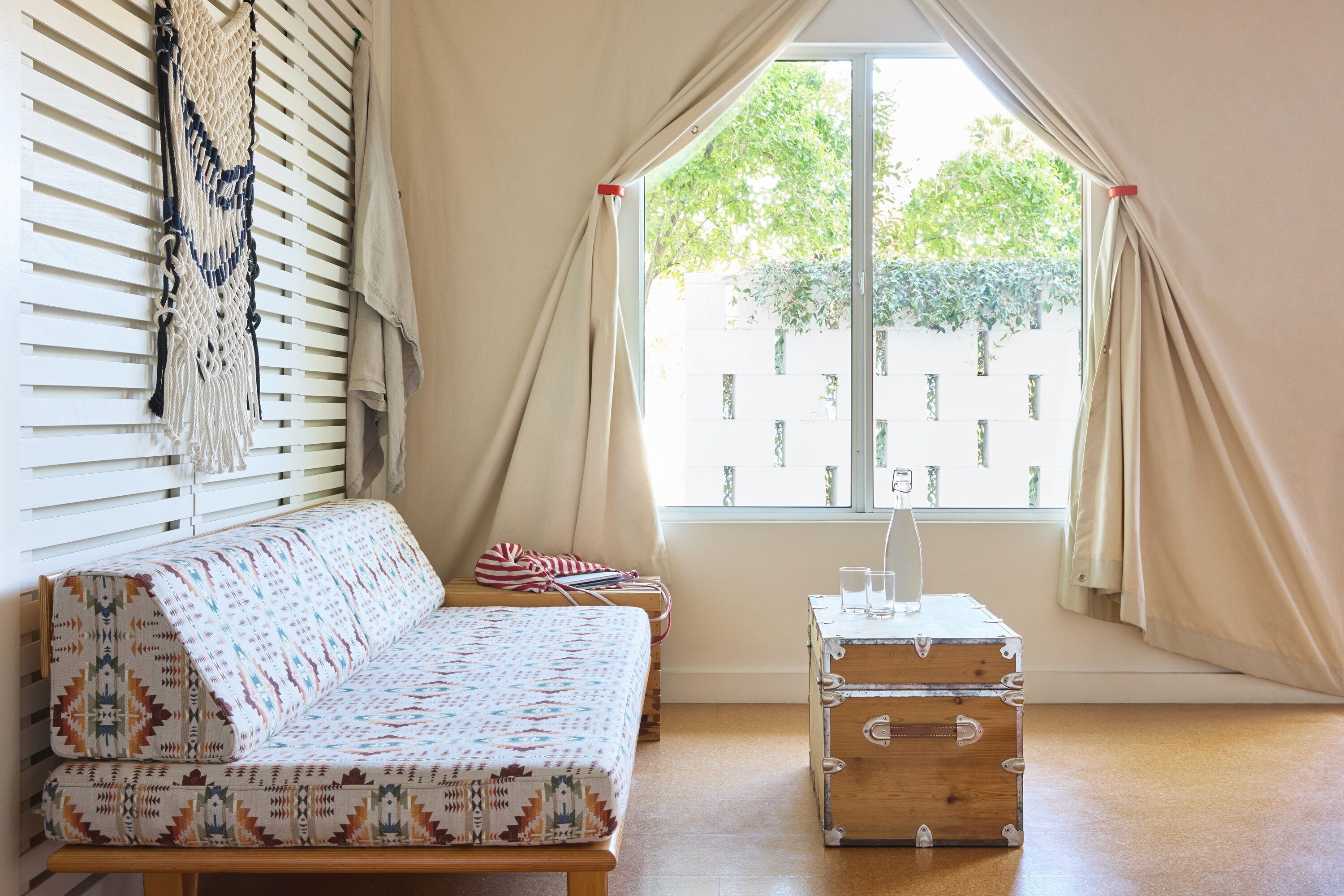 Une pièce avec un canapé à motifs, une commode en bois et une fenêtre avec des rideaux.