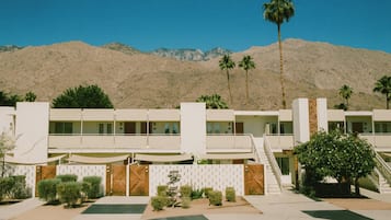 Un hotel moderno con techo plano, varios balcones y un paisaje desértico de fondo.