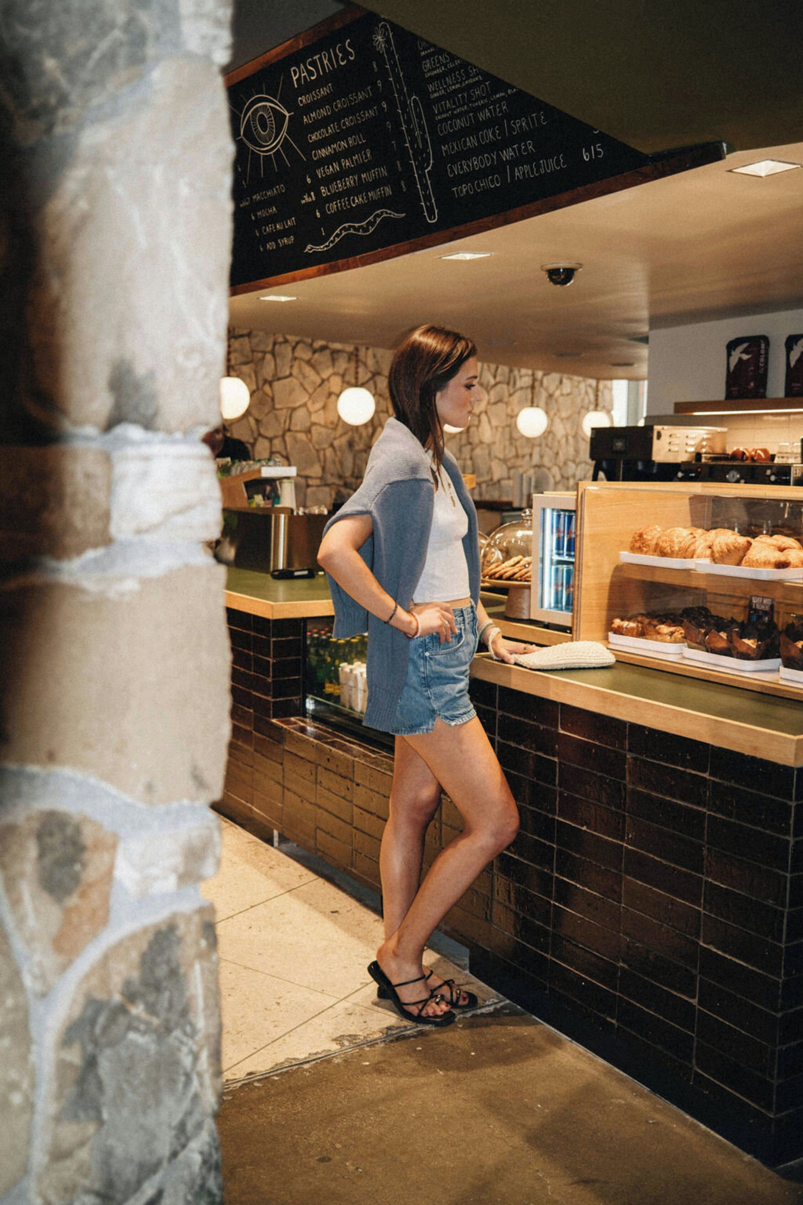A person standing at a counter with a menu listing pastries and beverages.