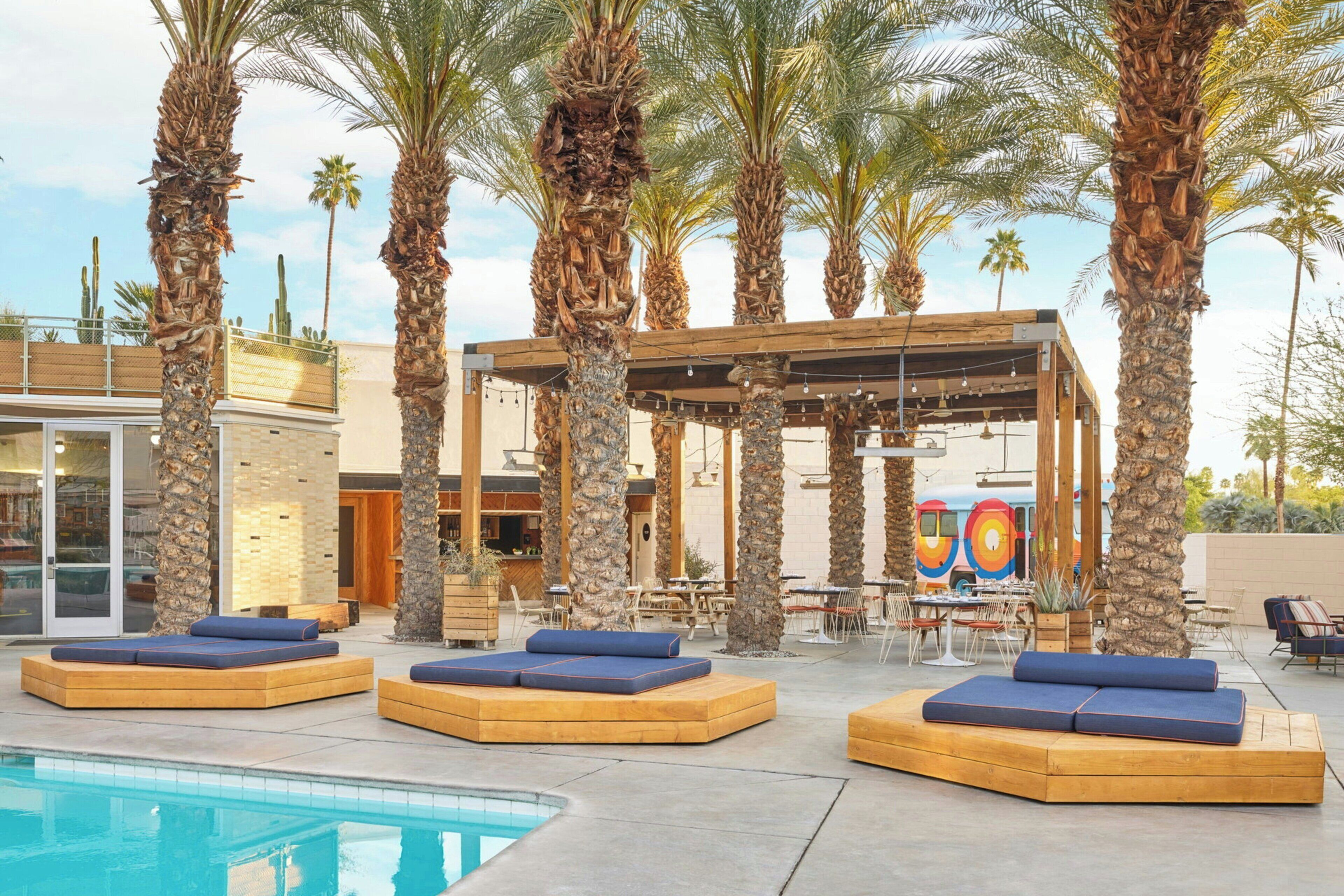 A poolside area with lounge chairs and a wooden pergola.
