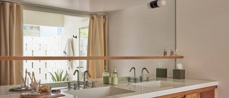 Un baño con un espejo grande, dos lavamanos y armarios de madera.
