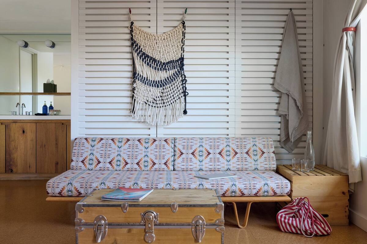 A cozy room with a patterned sofa, a wooden chest, and a woven wall hanging.