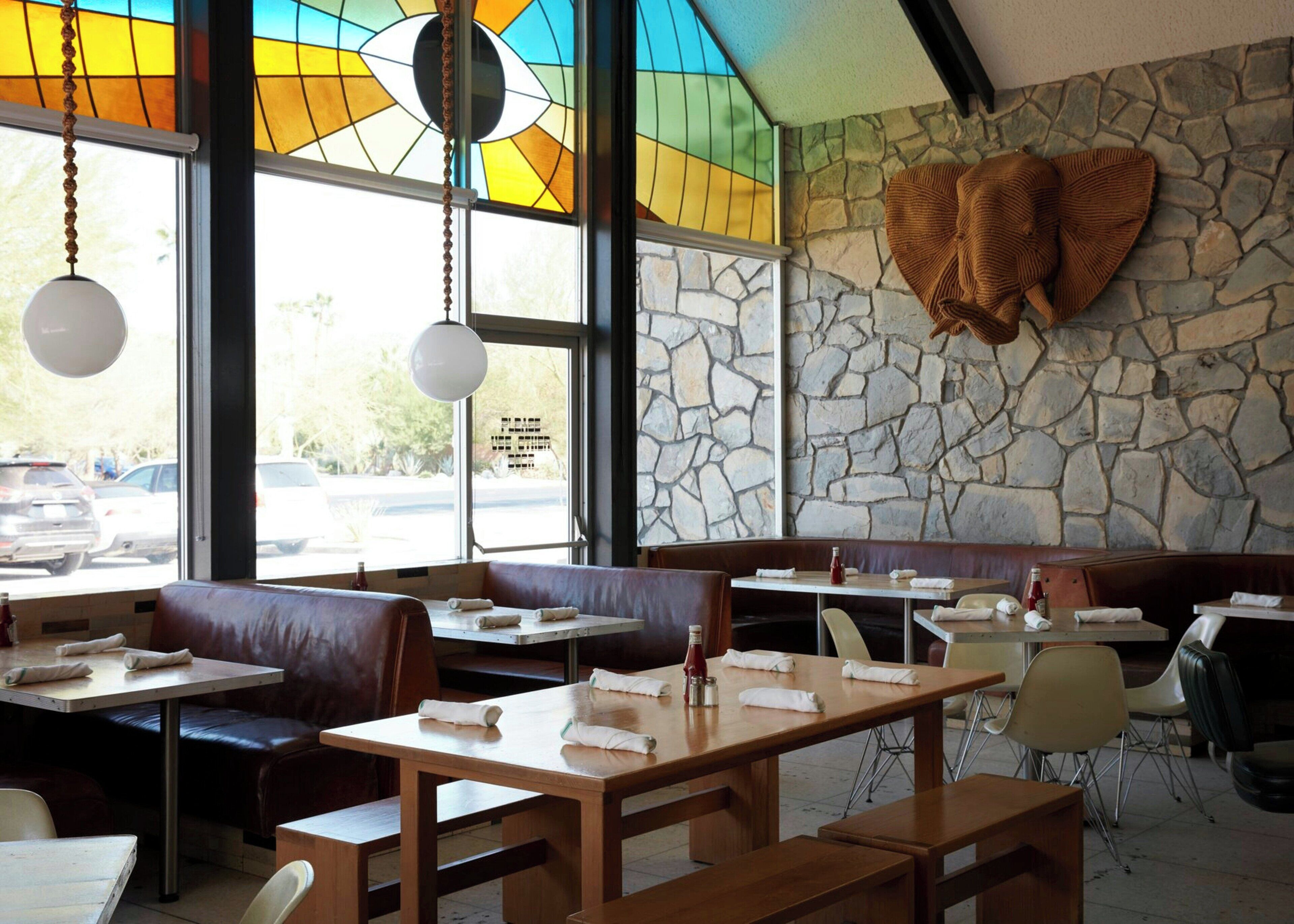 A restaurant interior with stone walls, wooden tables, and leather booths.