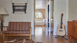 A cozy living room with a striped sofa, a guitar, and a cowhide rug. - Ace Hotel & Swim Club Palm Springs (Palm Springs)