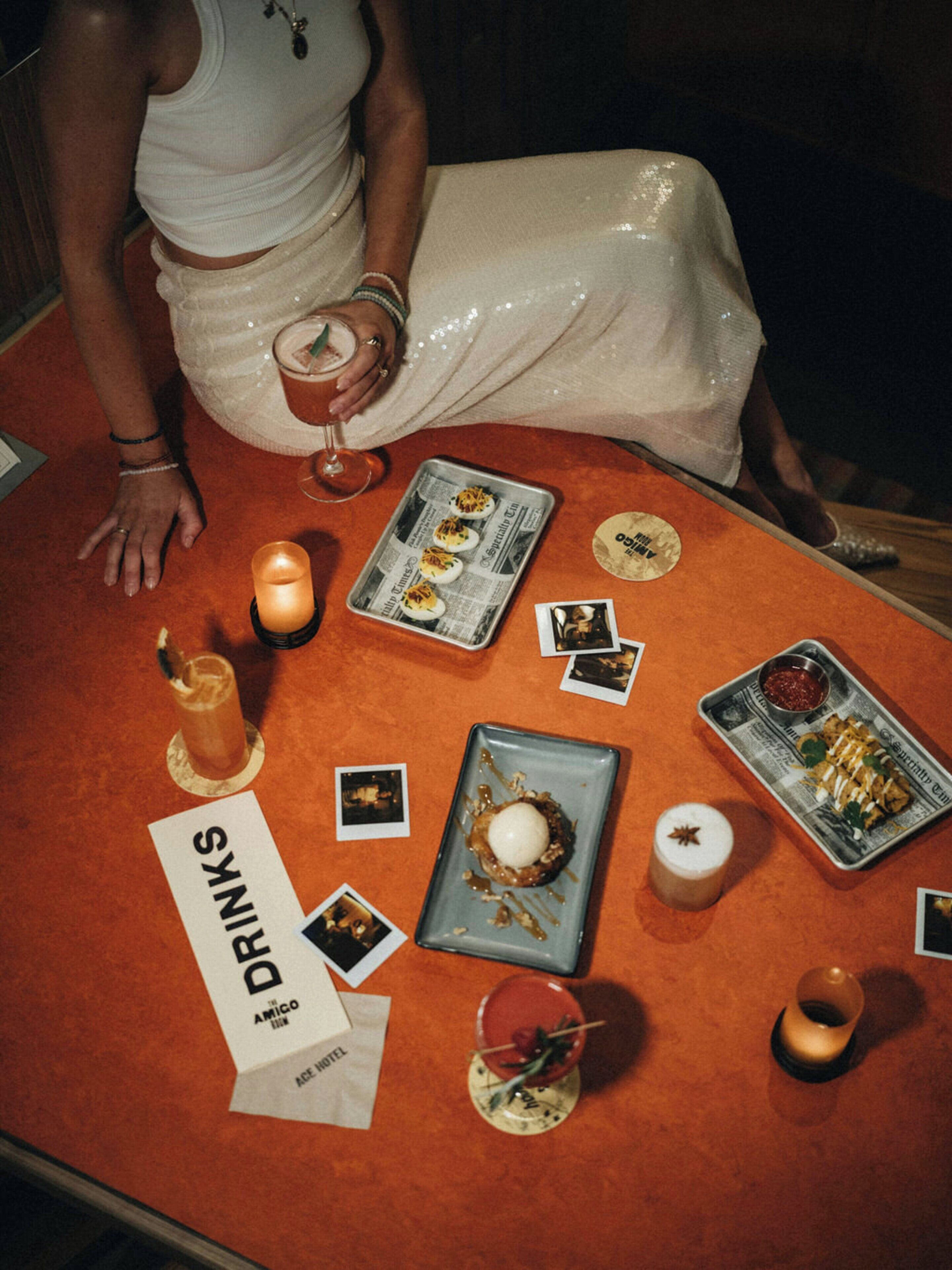 Une table avec divers plats et boissons, une bougie et un panneau indiquant le menu.