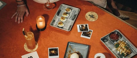 A table with various food items and drinks, a candle, and a menu sign.