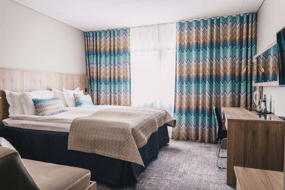 Una habitación de hotel con una cama, un escritorio y una silla.