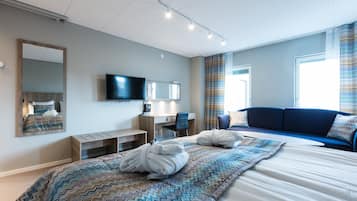 Una habitación de hotel moderna con una cama grande, un escritorio, una silla, un televisor y un sofá.
