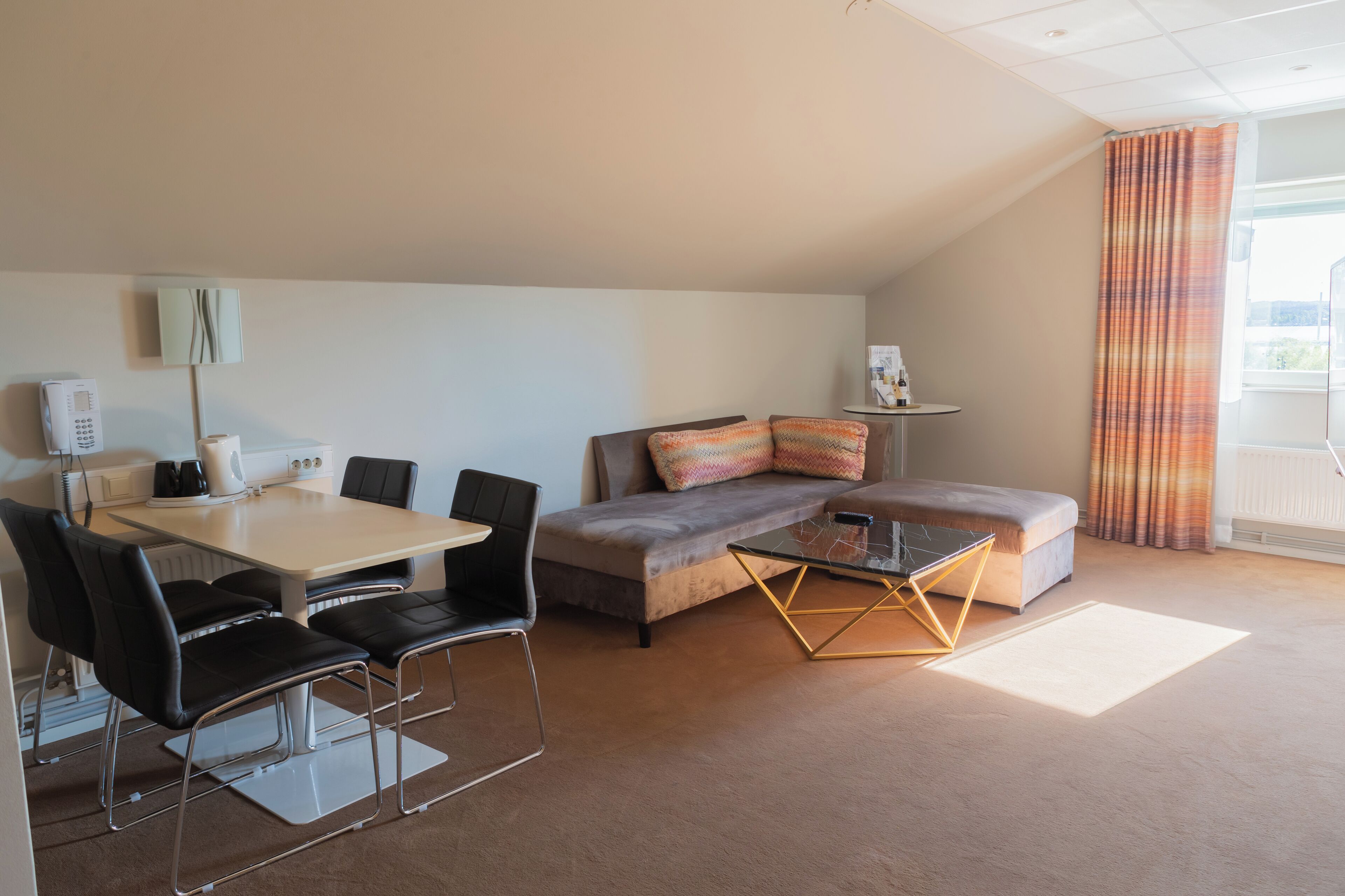 Ein modernes Wohnzimmer mit einer Couch, einem Couchtisch, einem Esstisch mit Stühlen und einem kleinen Beistelltisch.