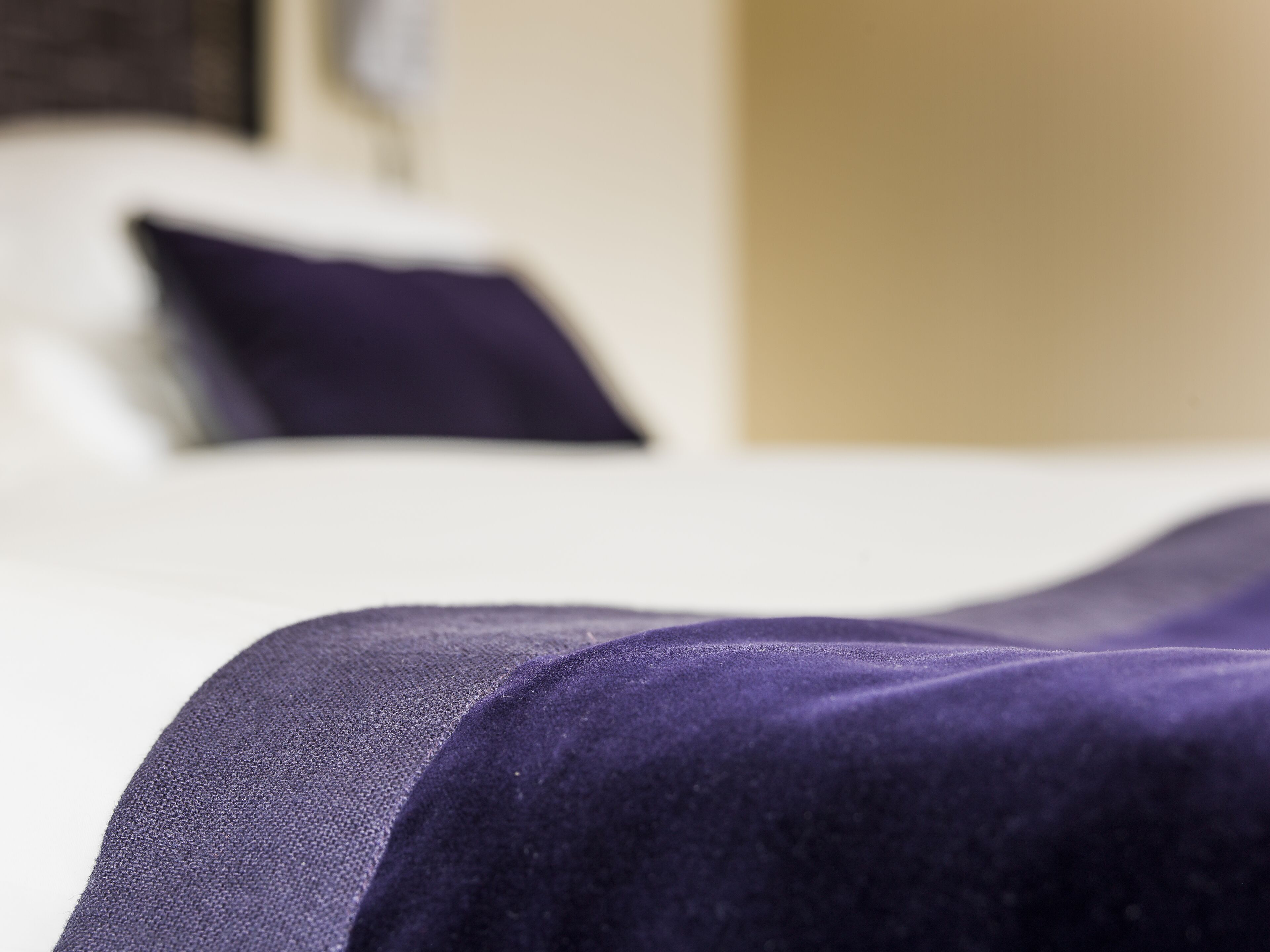 A close-up of a bed with a purple bedspread.