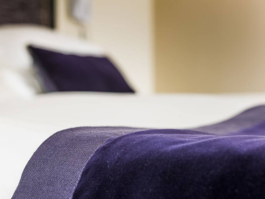 A close-up of a bed with a purple bedspread.