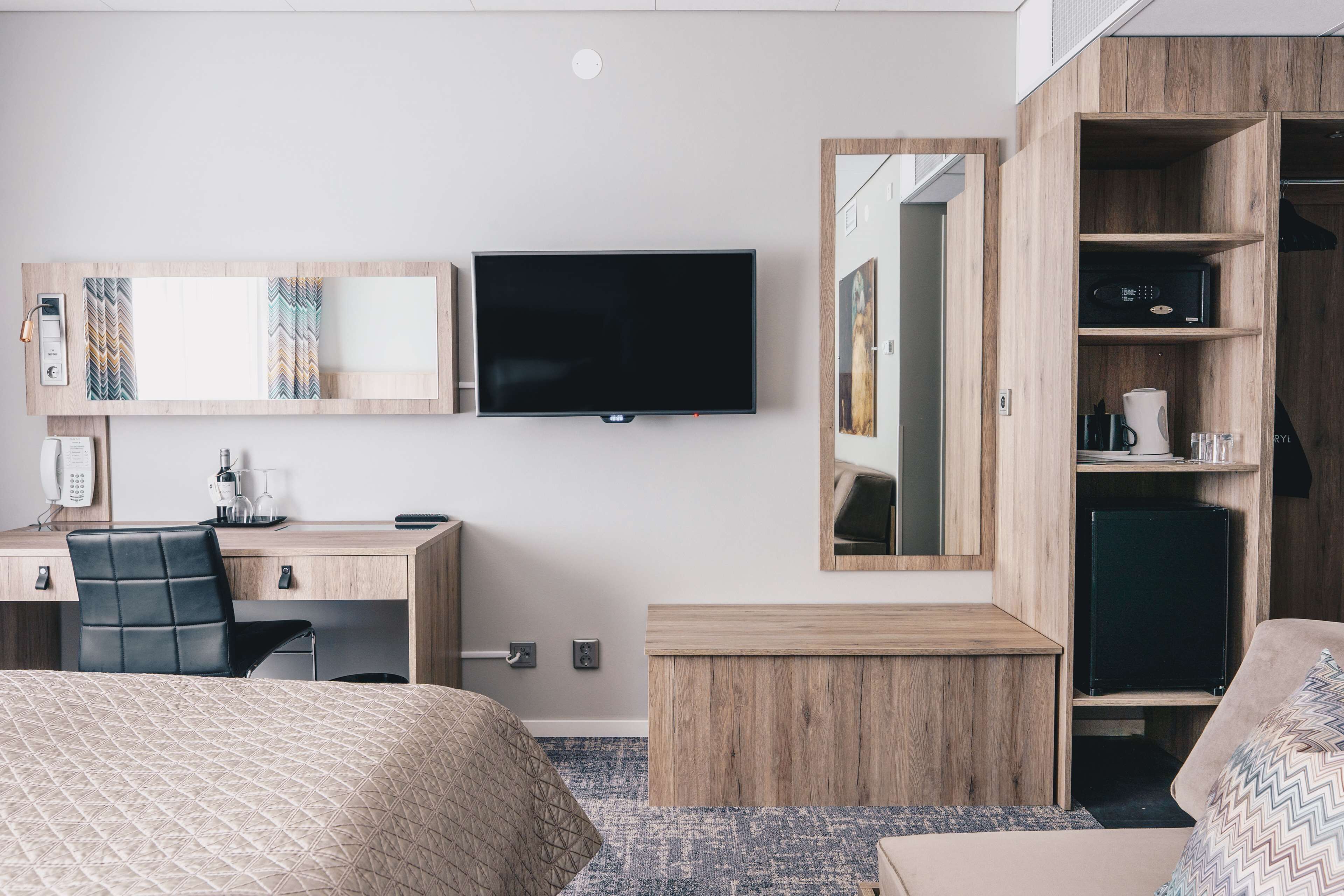 Une chambre d’hôtel comprenant un lit, un bureau avec une chaise, une télévision, une armoire et un miroir.