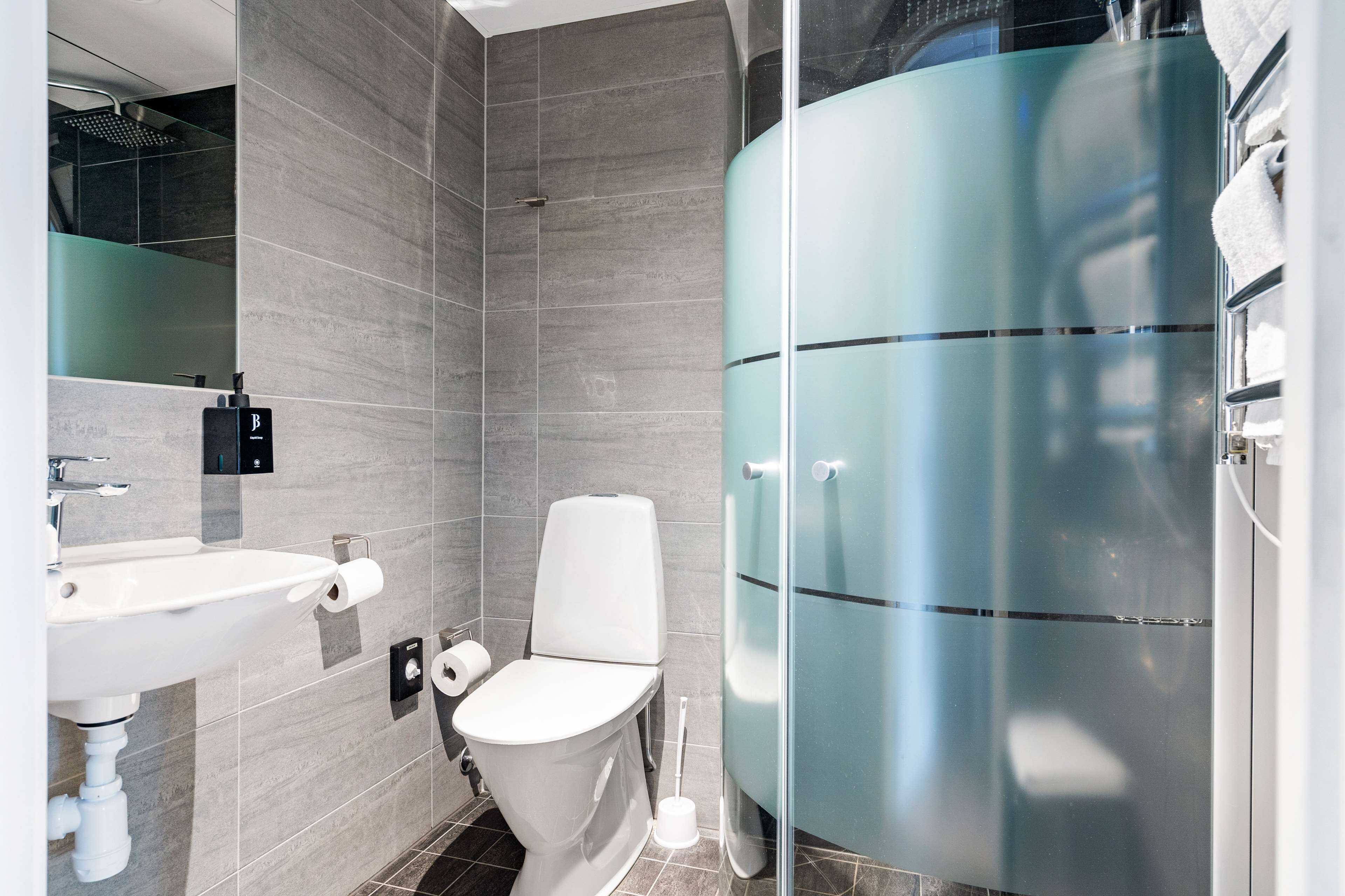 Een moderne badkamer met toilet, wastafel en douchecabine met glazen wanden.