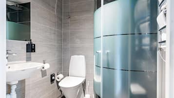Een moderne badkamer met toilet, wastafel en douchecabine met glazen wanden.
