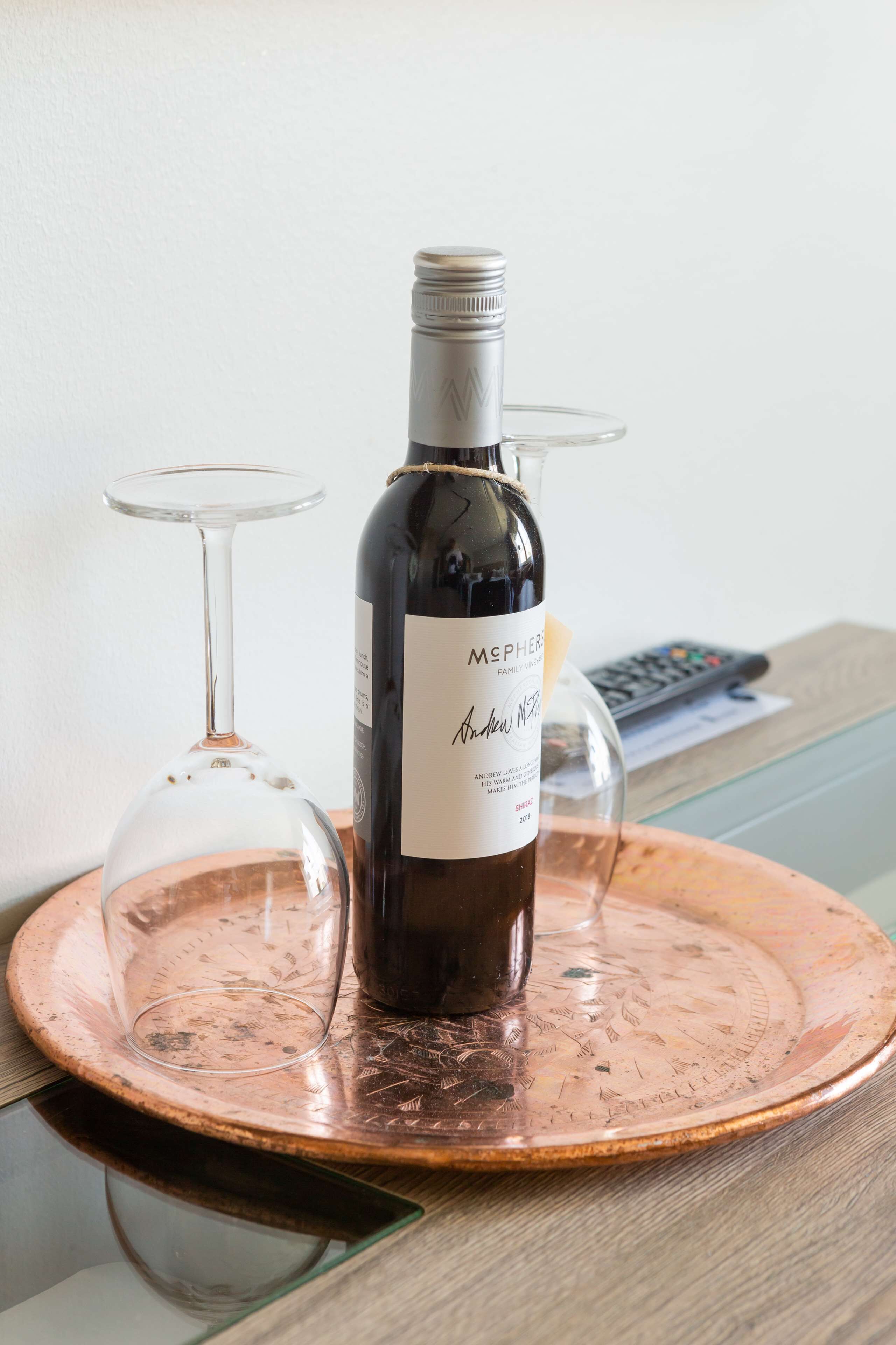 Una botella de McPherson Family Wines sobre una bandeja de cobre con dos copas de vino.
