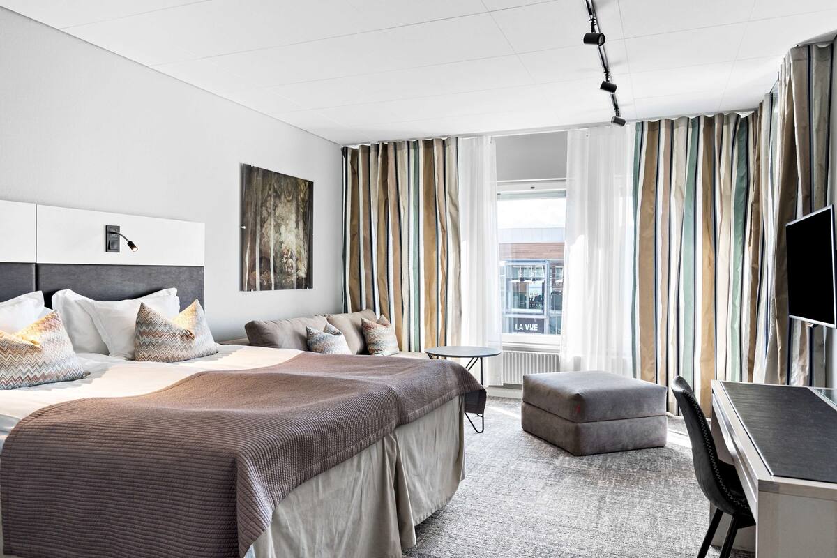 Un hotel moderno con una cama grande, un escritorio y vistas a la ciudad.