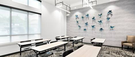A modern conference room with multiple tables and chairs, large windows, and a decorative wall with blue star-shaped ornaments.