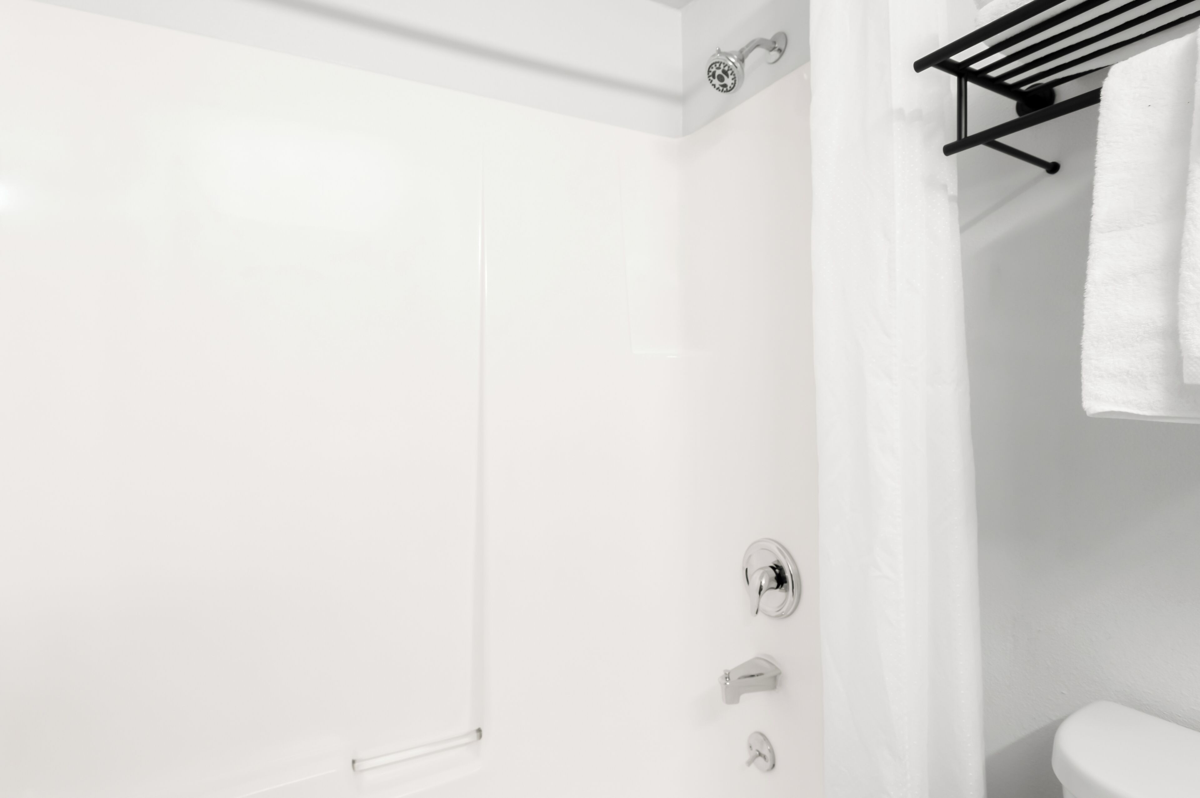 Een moderne badkamer met een witte douche, toilet en handdoekhouder.