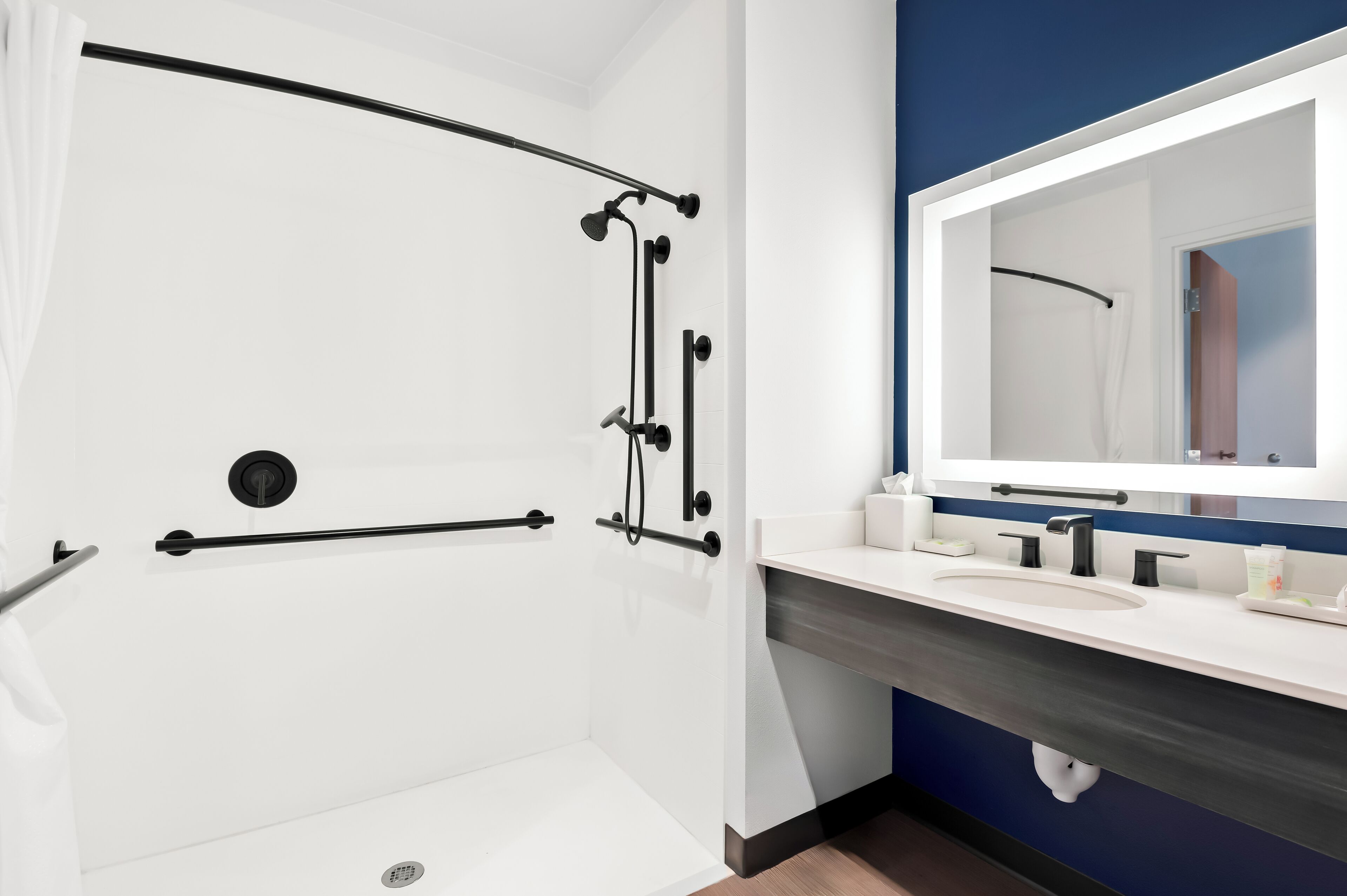 A modern bathroom with a walk-in shower, a large mirror, and a vanity with a sink.
