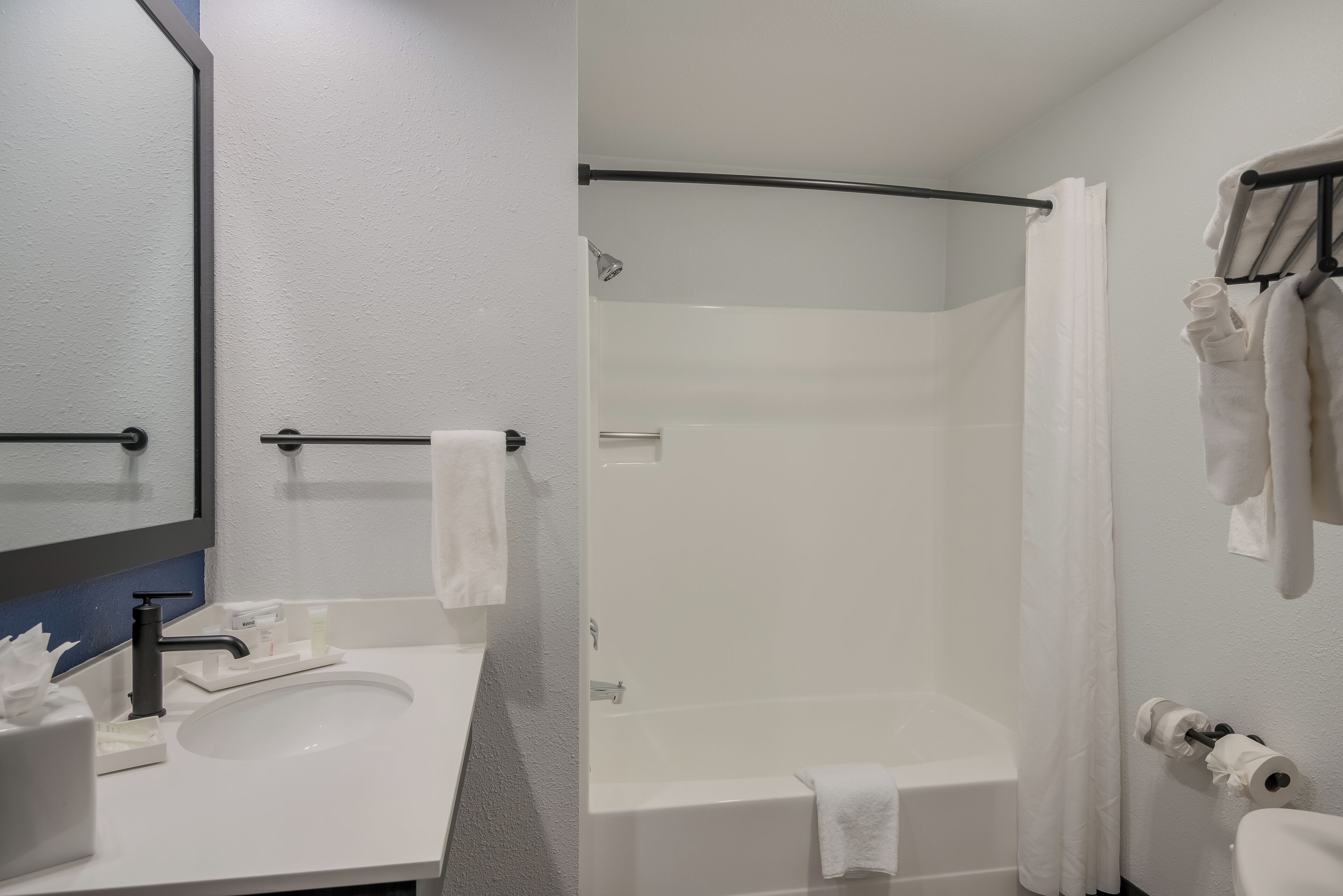 A bathroom with a sink, mirror, toilet, and bathtub.