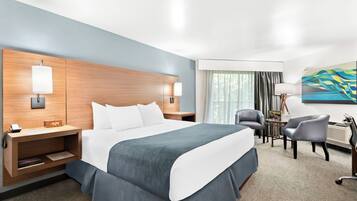 A hotel room with a large bed, bedside tables, a desk, a chair, and a painting on the wall.