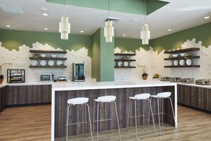 A modern kitchen with a central island, bar stools, and decorative shelves.