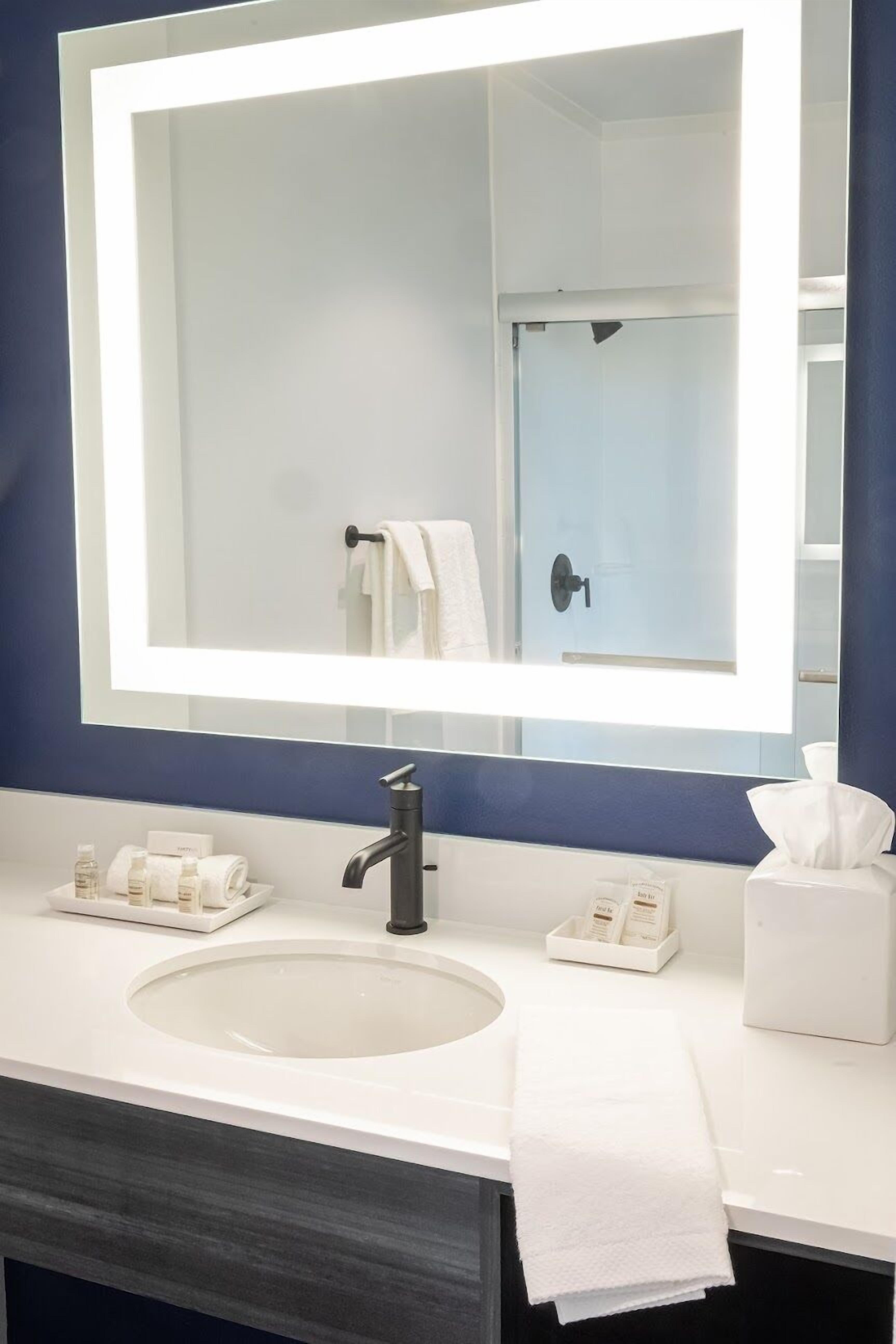 A bathroom with a large mirror, white sink, and a towel rack.