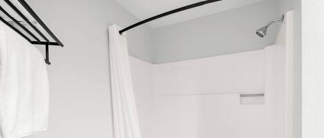 Un baño moderno con ducha, toallero y retrete.