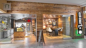 A modern coffee shop with a rustic wooden interior, a visible menu board, and a seating area with chairs and tables.