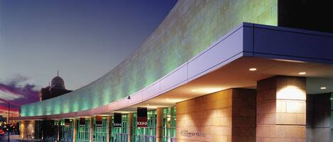 A modern building with a curved facade, large glass windows, and a prominent entrance with signage.