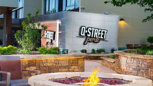 A Q STREET hotel exterior with a stone fire pit and outdoor seating area.