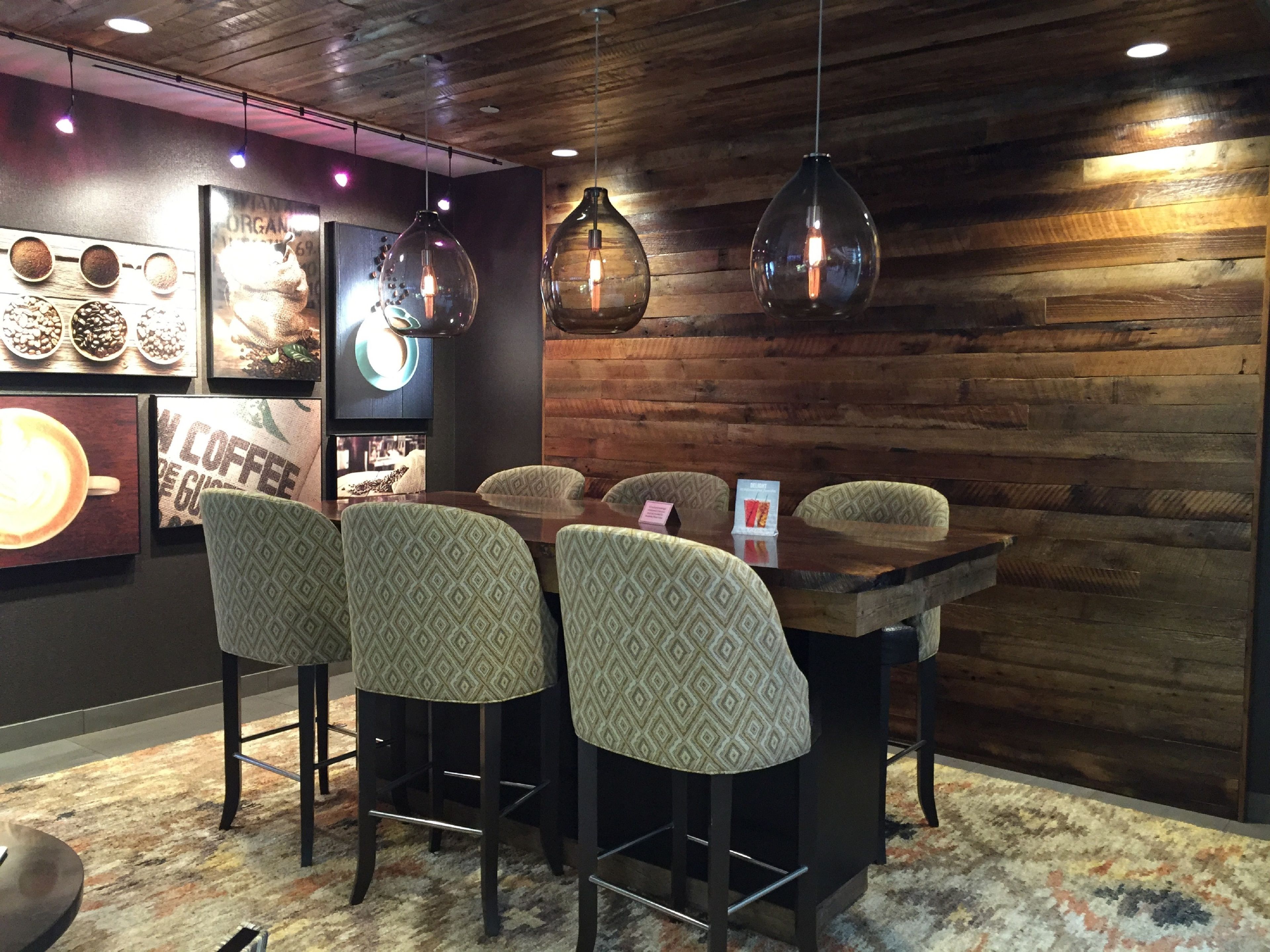 Un café con pared de madera rústica, luces colgantes y taburetes de barra con estampado.