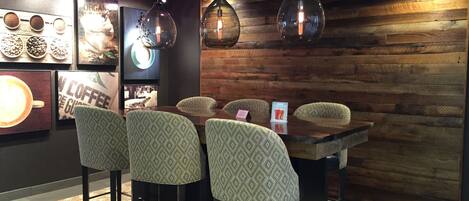 Un café con pared de madera rústica, luces colgantes y taburetes de barra con estampado.