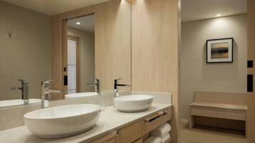 A modern bathroom with two large sinks, a mirror, and a bench.