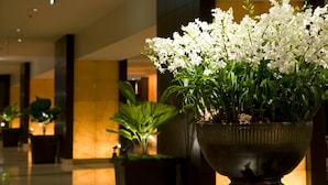 Un vestíbulo con una planta grande en maceta con flores blancas, suelo de mármol y una decoración de estilo moderno.