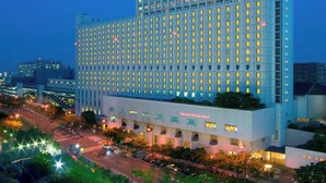 Un hotel moderno de gran altura, con varios pisos, una entrada destacada y una fachada bien iluminada.