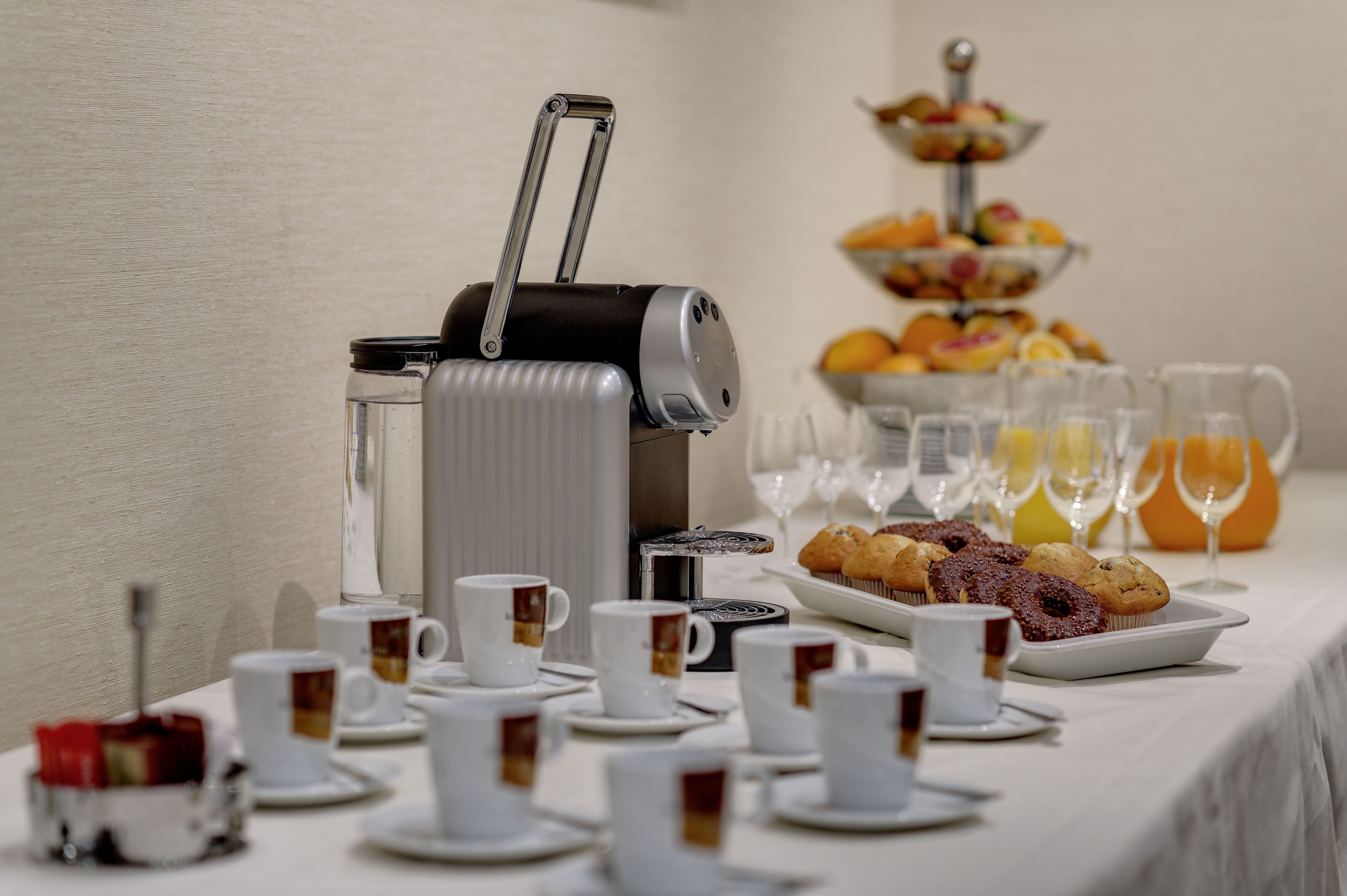 Un bufé de desayuno con café, té, muffins y fruta.