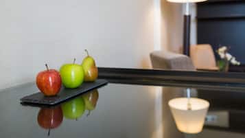 A polished table with three apples and a lamp in the background.