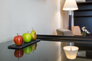 A polished table with three apples and a lamp in the background.
