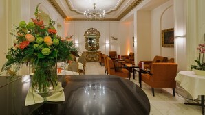 A hotel lobby with a grand chandelier, a large mirror, and comfortable seating areas. - Hotel Euler (Basel)
