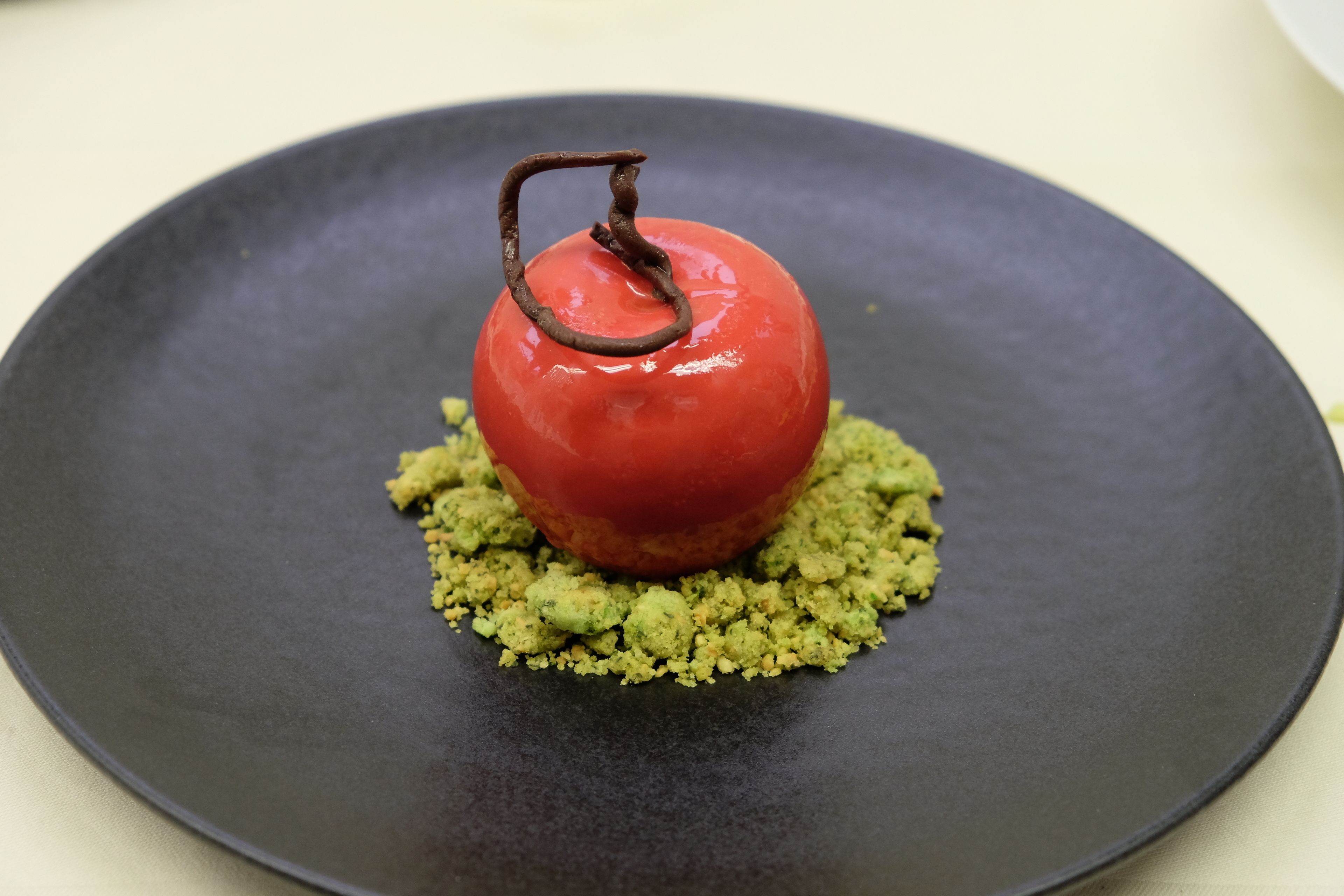 A dessert on a dark plate with a green base.