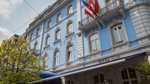 A hotel with a blue facade, a balcony with flags, and a sign for "EULER BAR" below. - Hotel Euler (Basel)