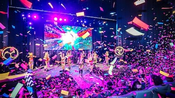 Un escenario con artistas y confeti, rodeado de público.