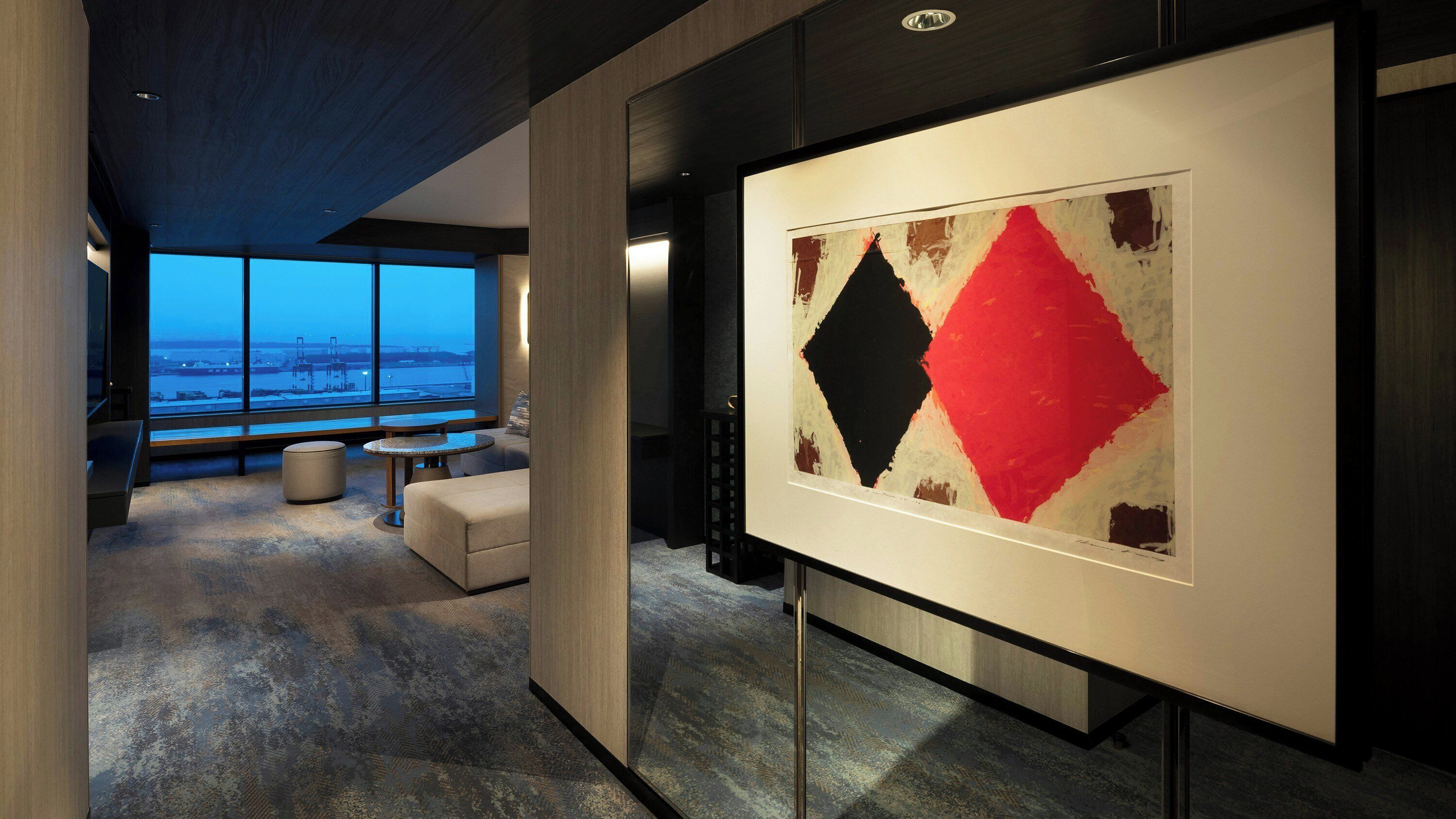 A modern hotel lobby with a large window offering a view of the cityscape at dusk.