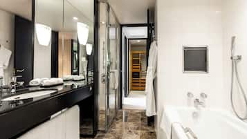 A modern bathroom with a large mirror, a glass shower enclosure, a bathtub, and a vanity with a black countertop.
