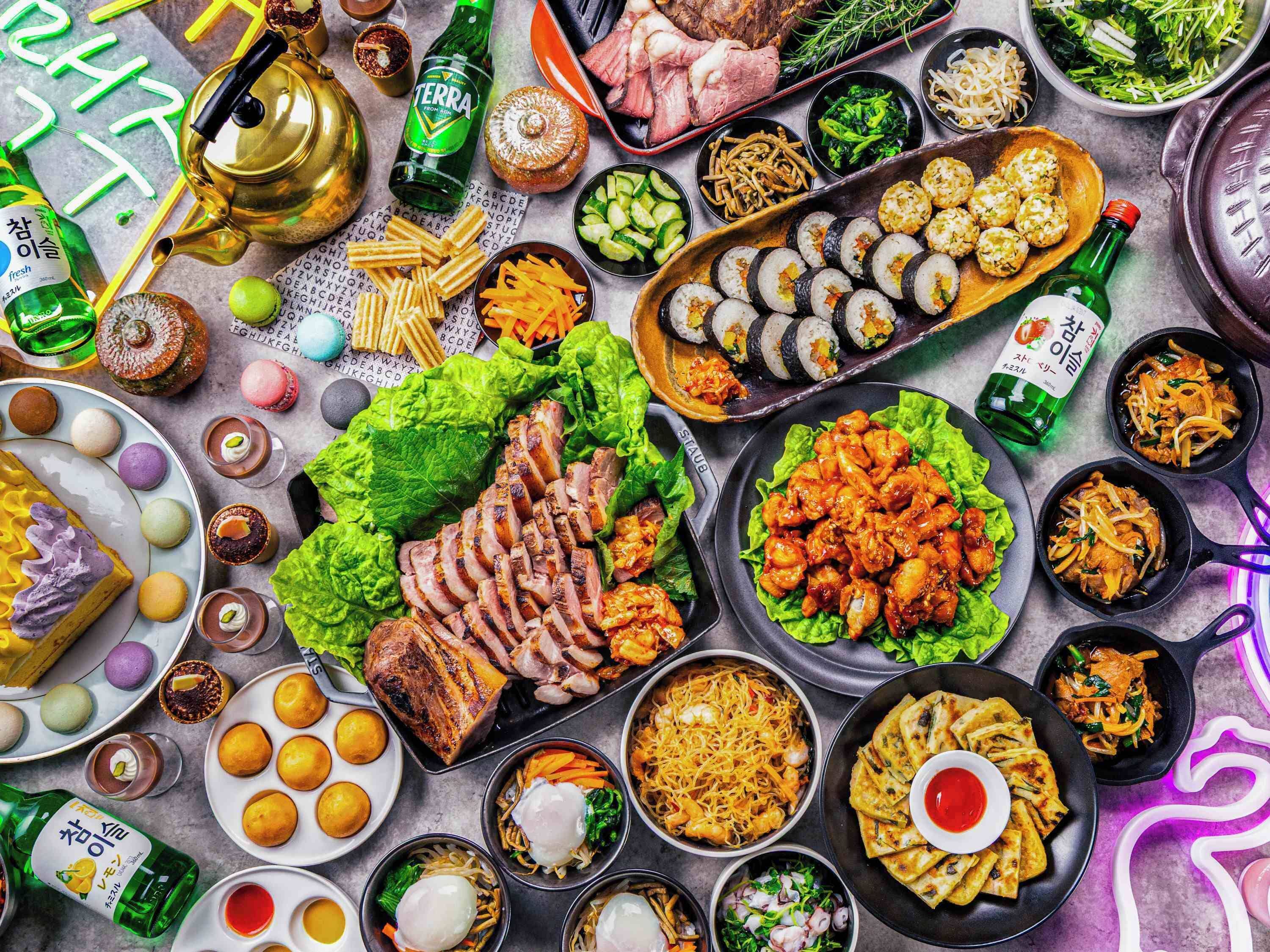 A variety of dishes and drinks on a table, including sushi, meat, and vegetables.