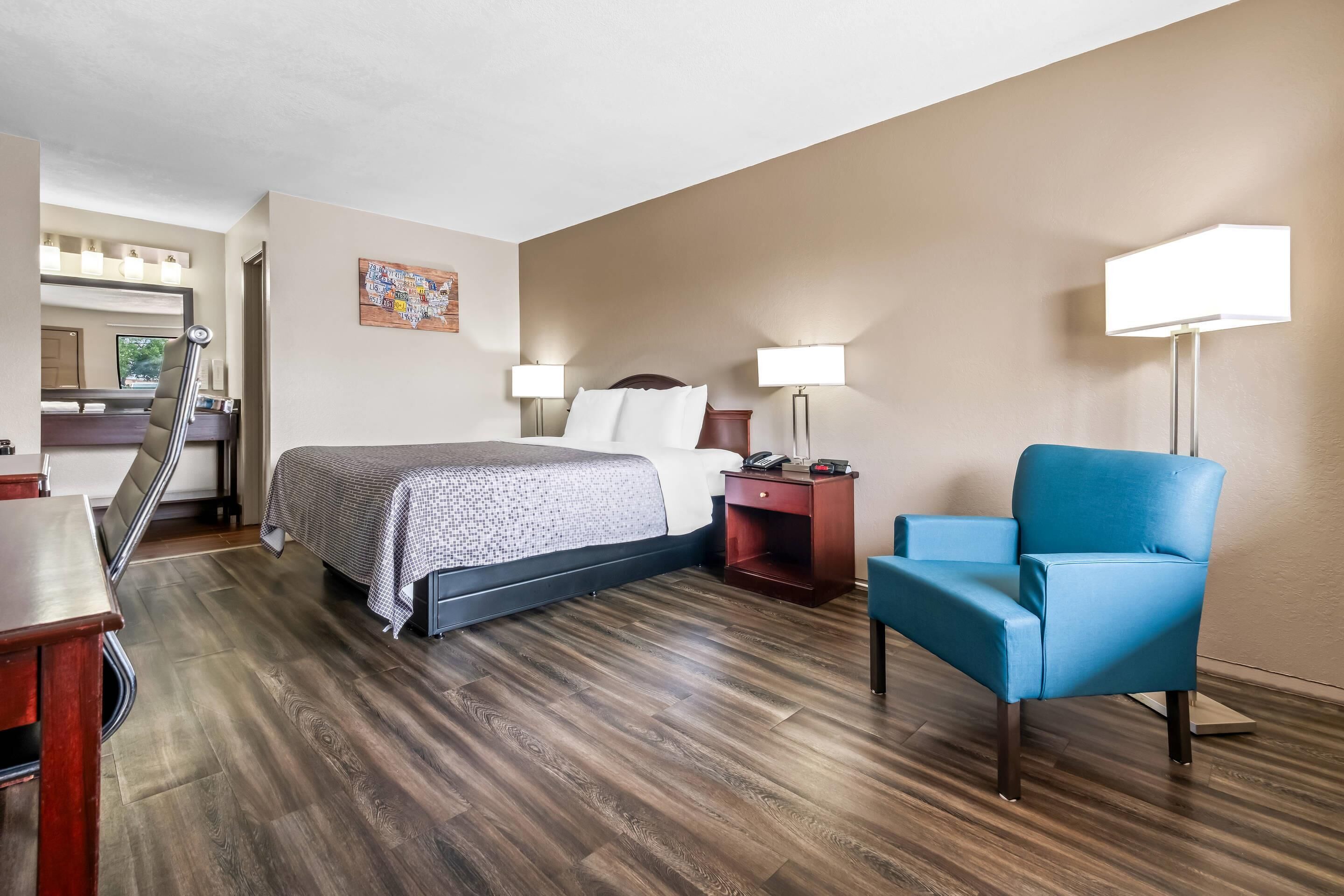 Una habitación de hotel con cama, mesitas de noche, escritorio, silla y lámpara.